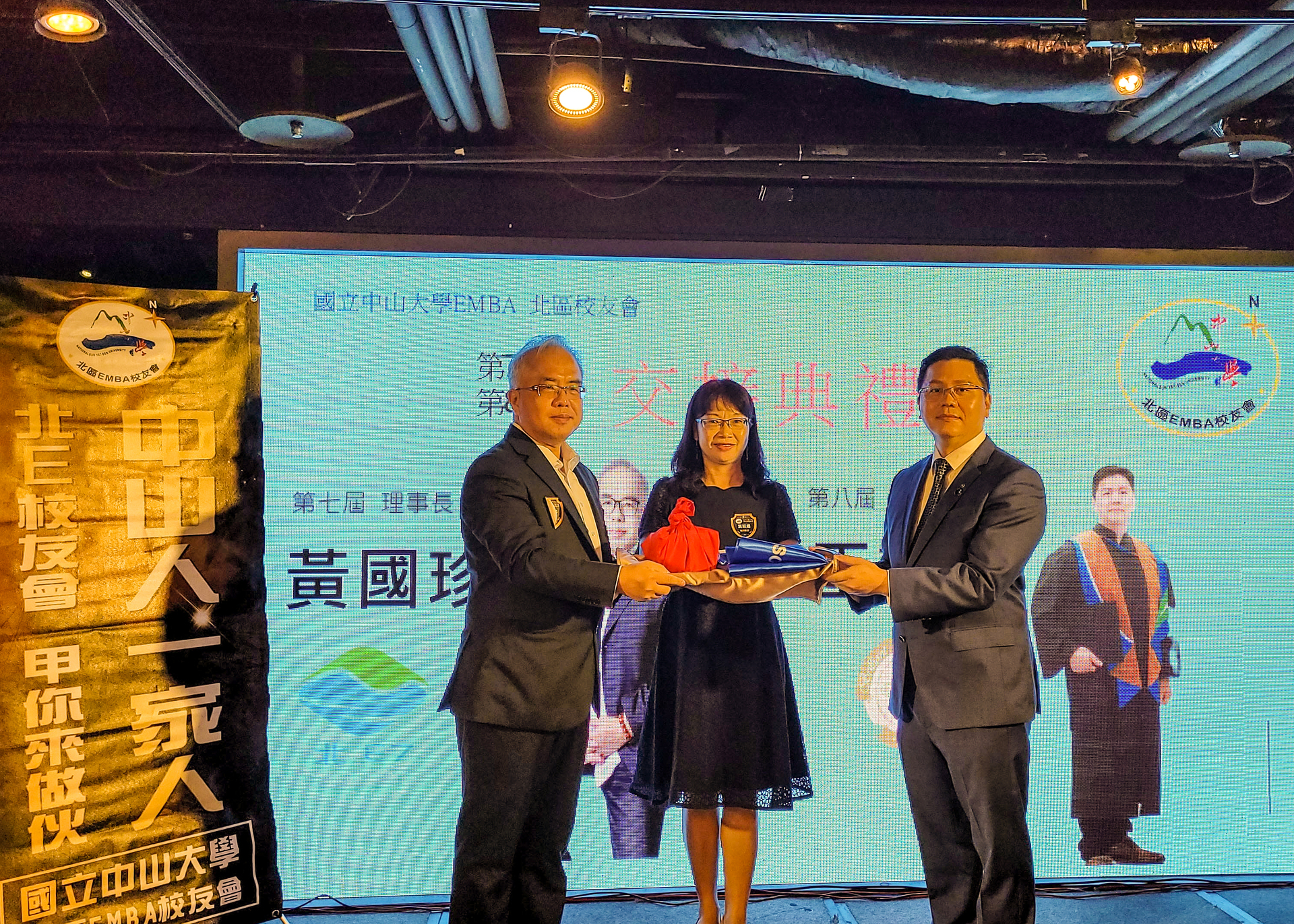 第七屆理事長黃國珍(左）)交棒予第八屆理事長王群文(右)，並由管院葉淑娟院長(中)擔任監交人圖片